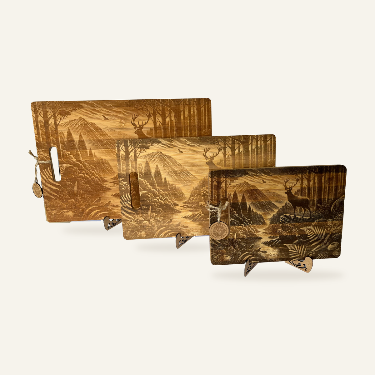 Three Stag’s Edge engraved wooden boards displayed together on decorative stands against an ivory background.
