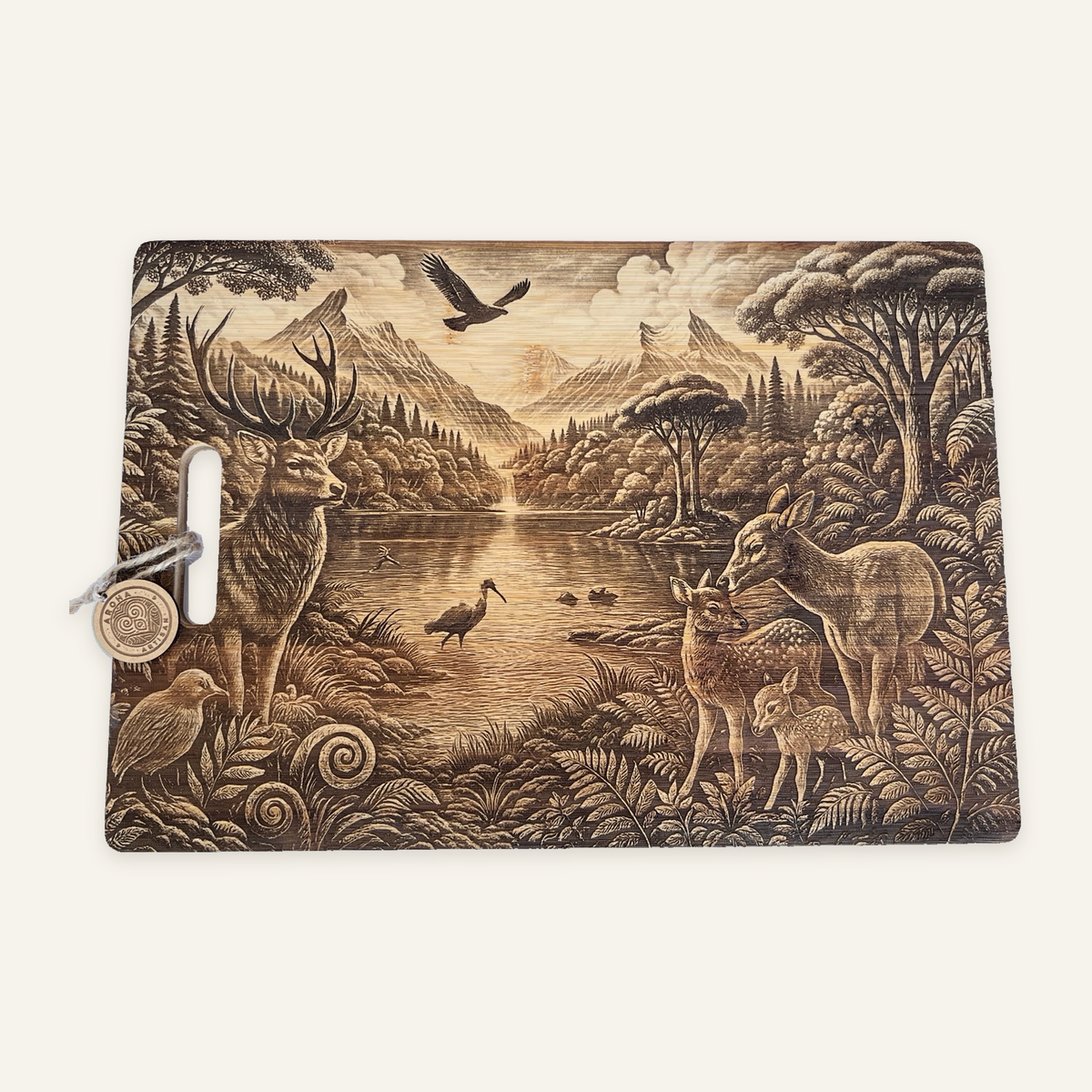 Where We Belong engraved wooden board with a stag, doe and two fawns beside a lake, mountains, birds and ferns, with an Aroha tag on an ivory background.
