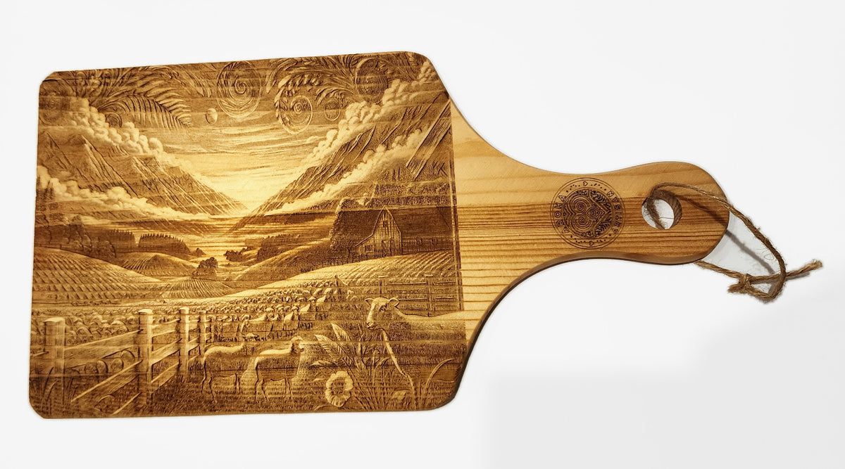 Sheep Farm design on an Aroha Artisan mini engraved wooden board, showing sheep, a barn, mountain scenery and handle.