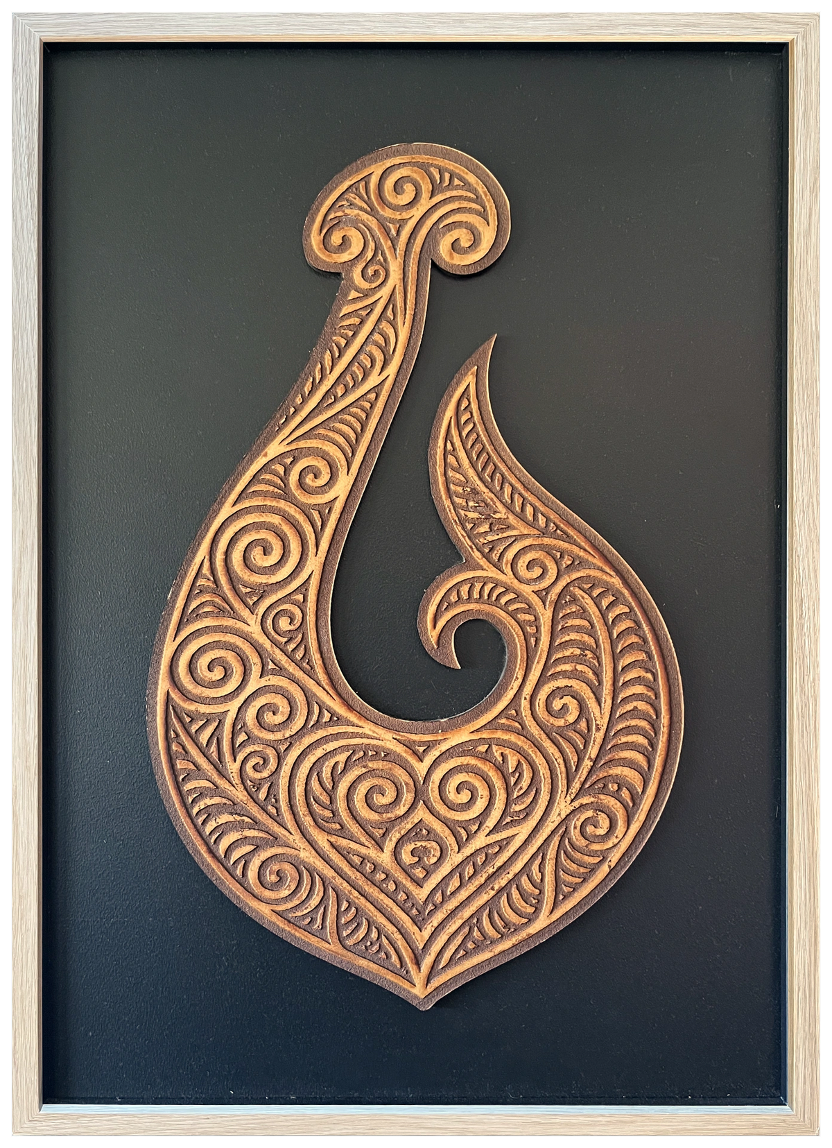Manaia engraved cutout artwork with black background and Ashwood frame — frame-finish composite and colour visualisation, not a new photograph.