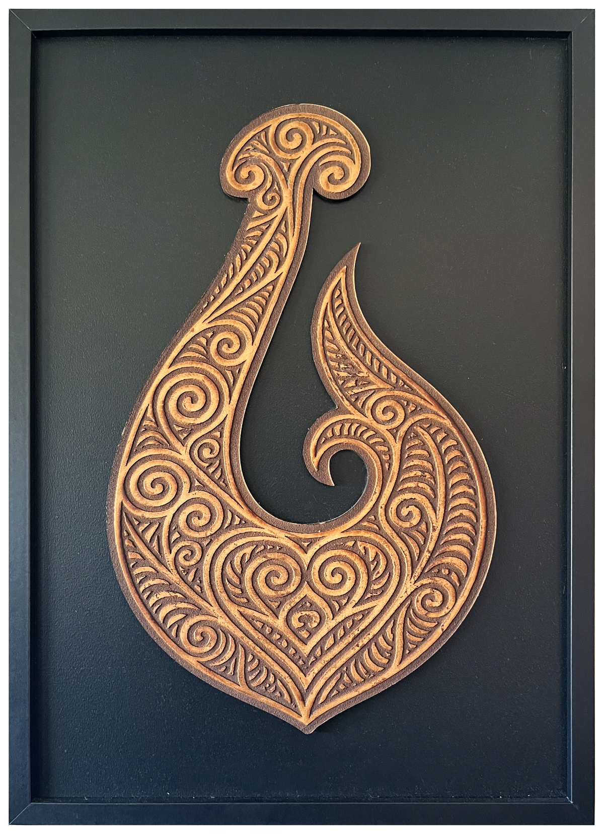 Manaia engraved cutout artwork in an A2-size black frame with a black background