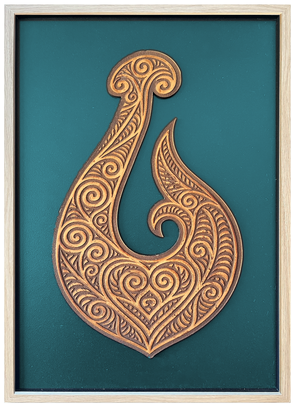 Manaia engraved cutout artwork with teal background and Ashwood frame — frame-finish composite and colour visualisation, not a new photograph.