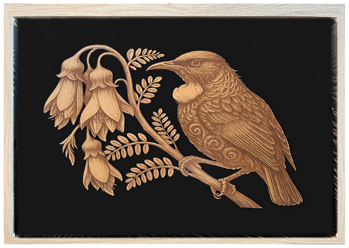 Tūī and Kōwhai engraved cutout artwork with black background and Ashwood frame — frame-finish composite and colour visualisation, not a new photograph.